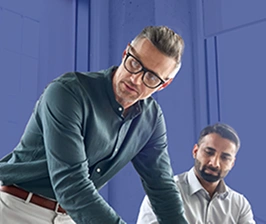 Cinco pessoas vestidas formalmente, reunidas em volta de uma mesa tendo uma reunião empresarial.